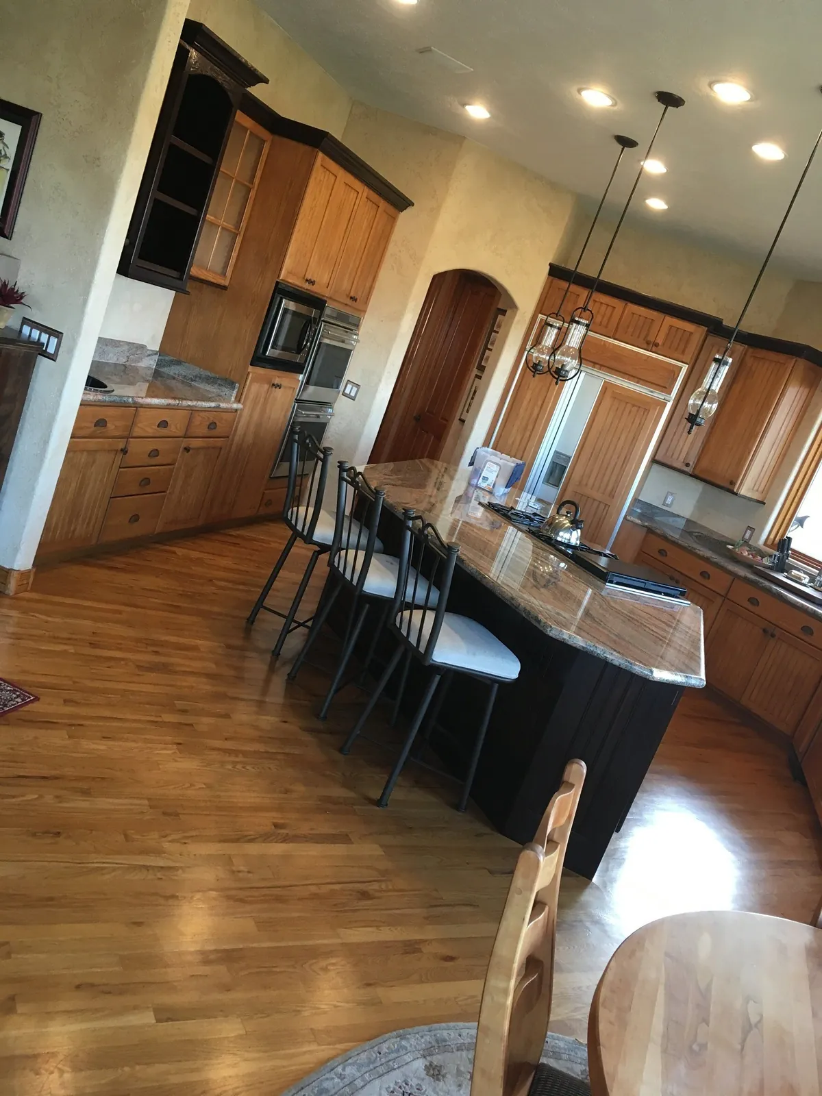 Refinished kitchen with dark island and warm perimeter
