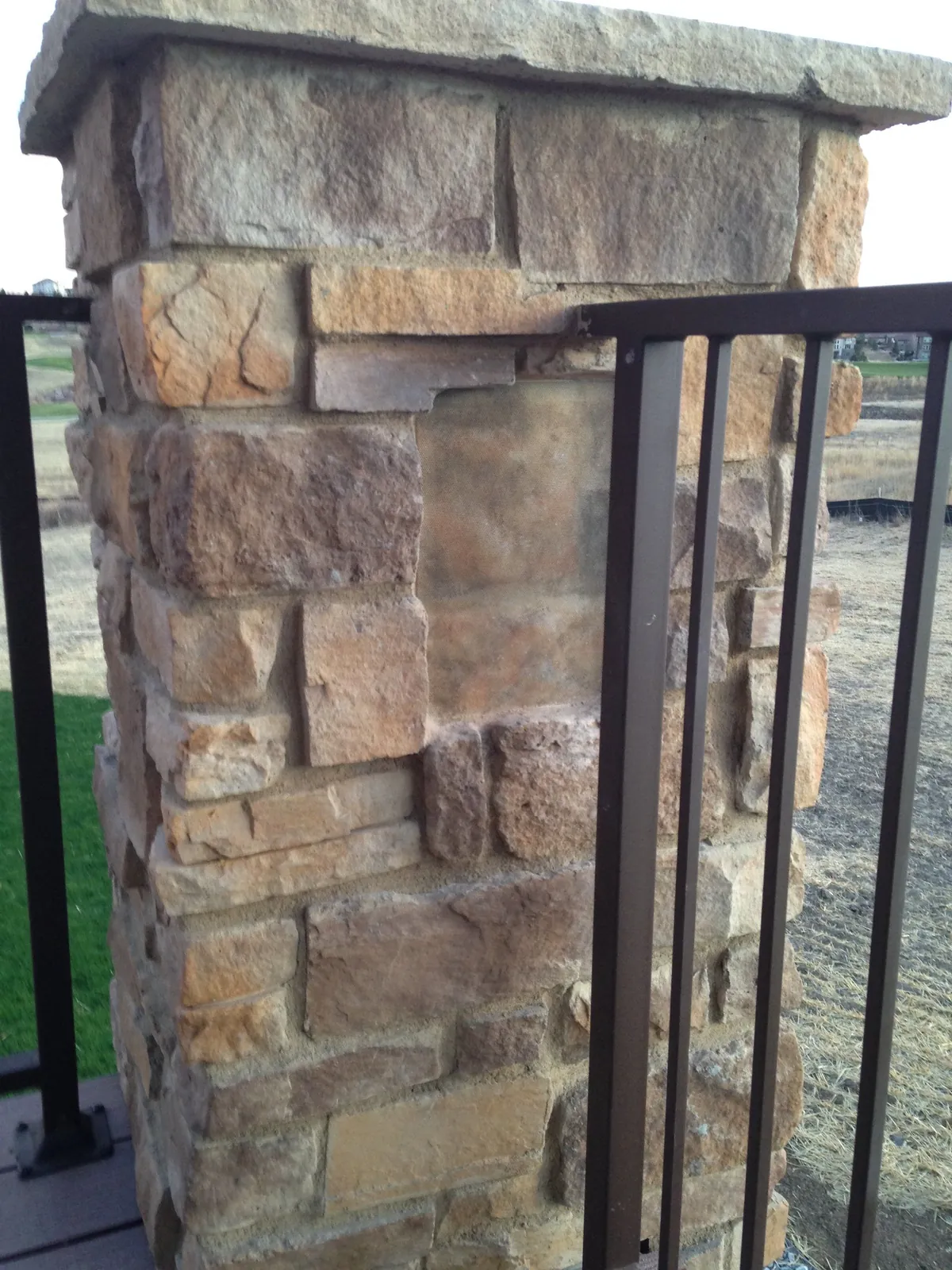 Speaker cover painted to match a stacked-stone column