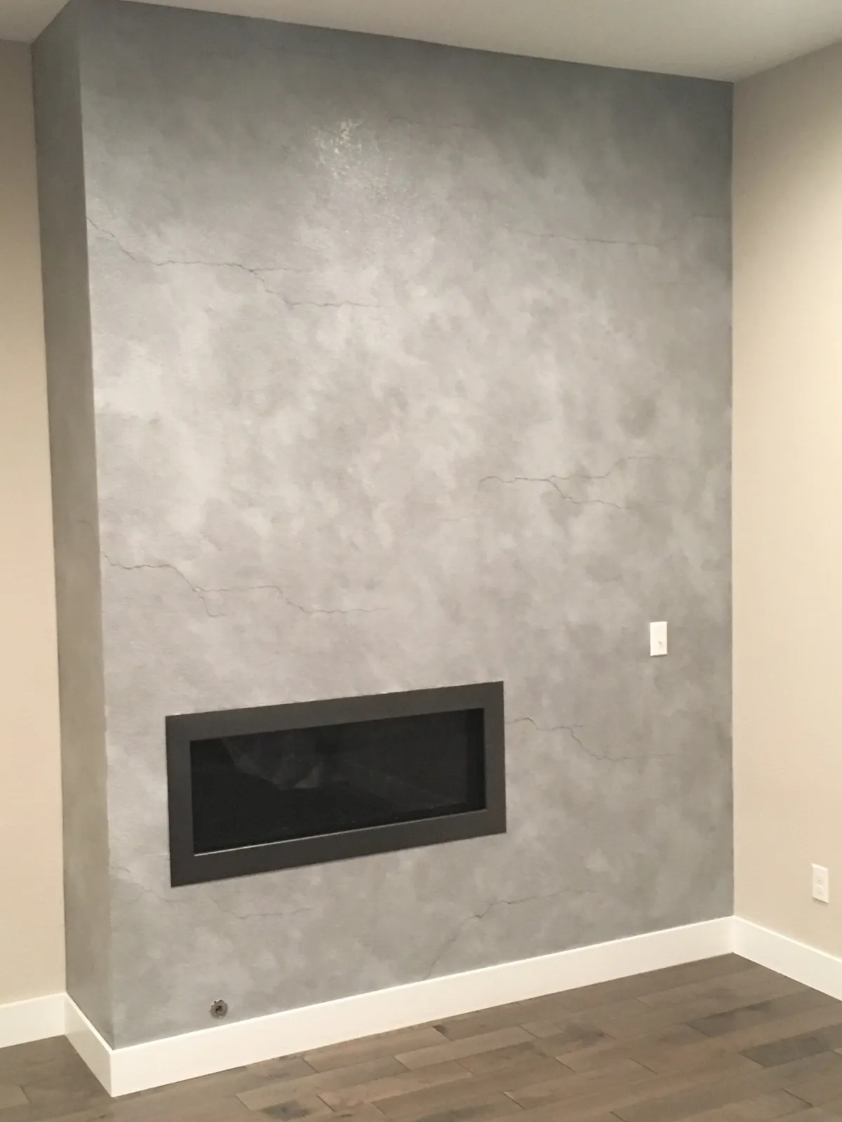 Grey metallic plaster feature wall around a linear fireplace